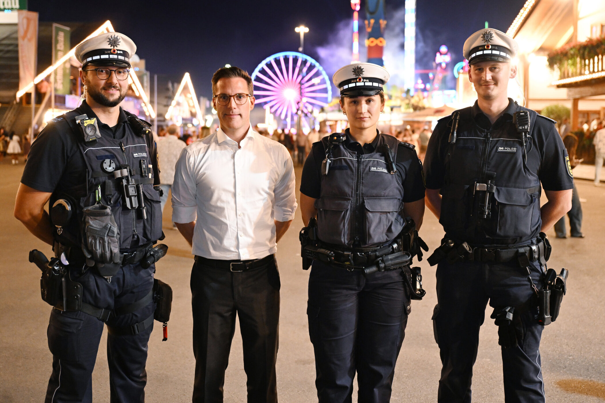 Vier Personen stehen vor einem beleuchteten Riesenrad bei Nacht.