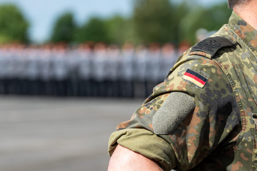 Nahaufnahme eines Arms in Tarnuniform, mit Deutschland-Flagge auf dem Ärmel.