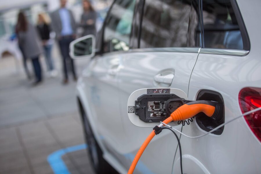 Ein weißes Auto wird mit einem orangefarbenen Kabel geladen.