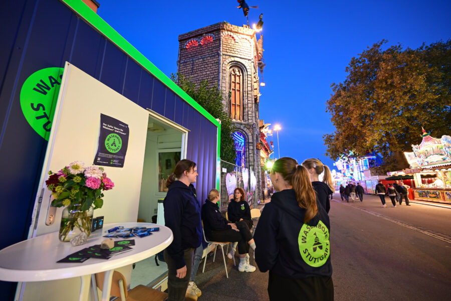 Eine Gruppe von sechs Personen in dunklen Hoodies steht vor einem Stand mit Blumen.