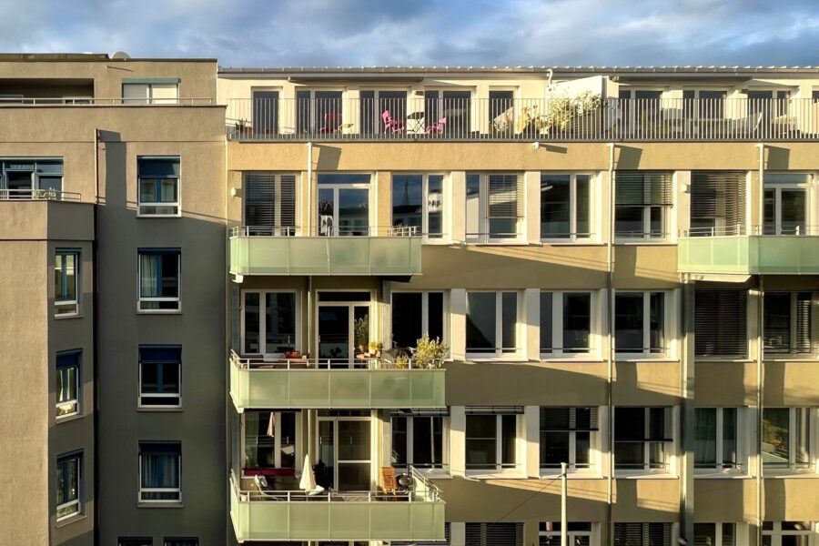 Mehrstöckiges Wohngebäude mit Balkonen und Fenstern bei Tageslicht.
