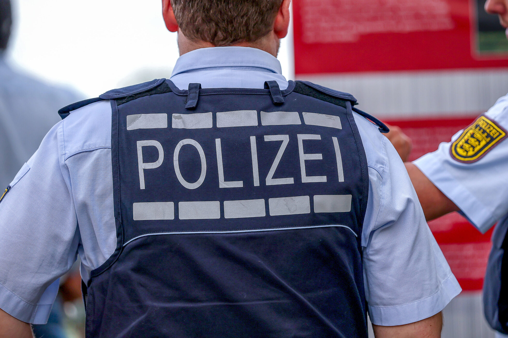 Zwei Polizisten von hinten, einer zeigt auf ein Schild.