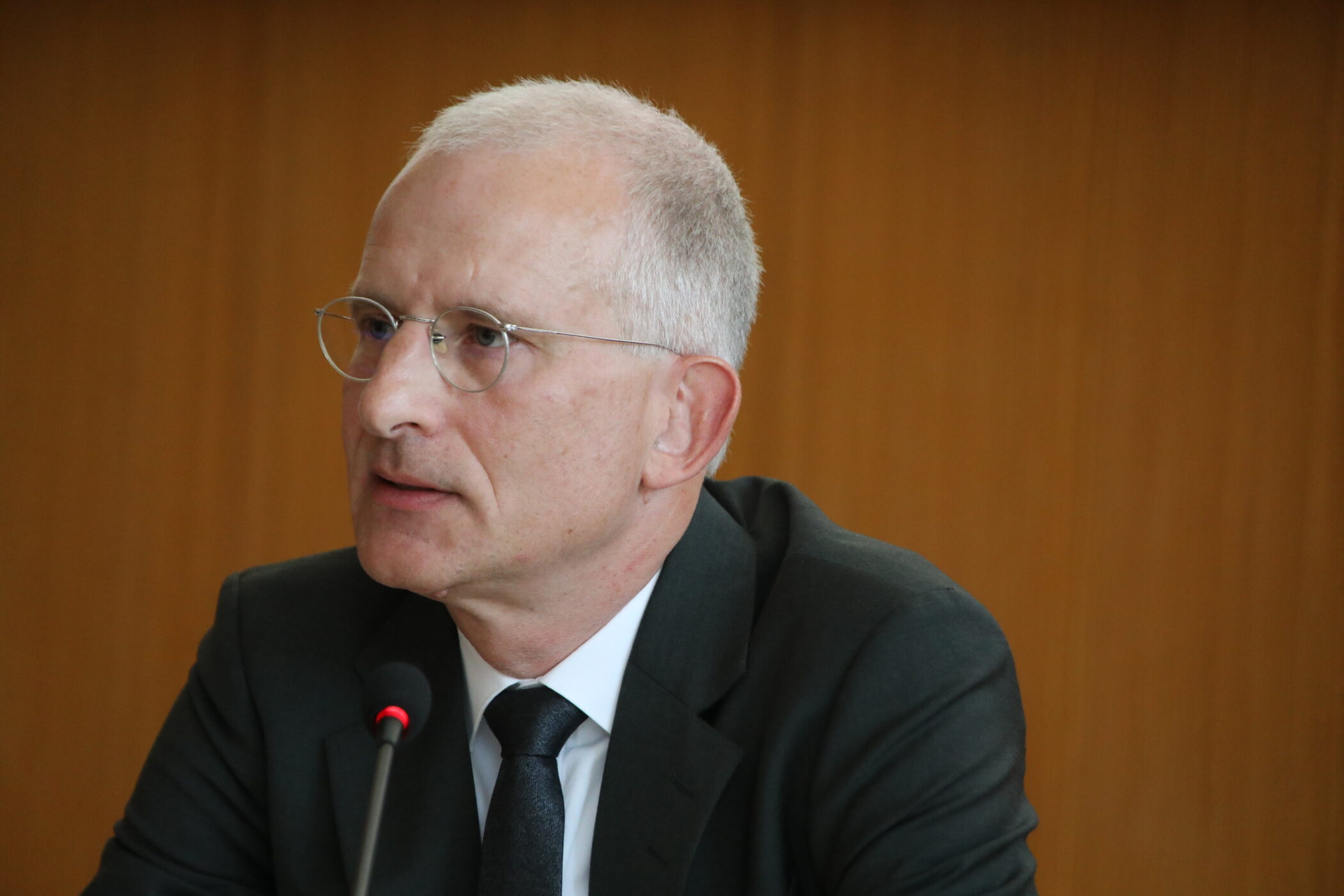 Eine Person mit Brille spricht in ein Mikrofon.