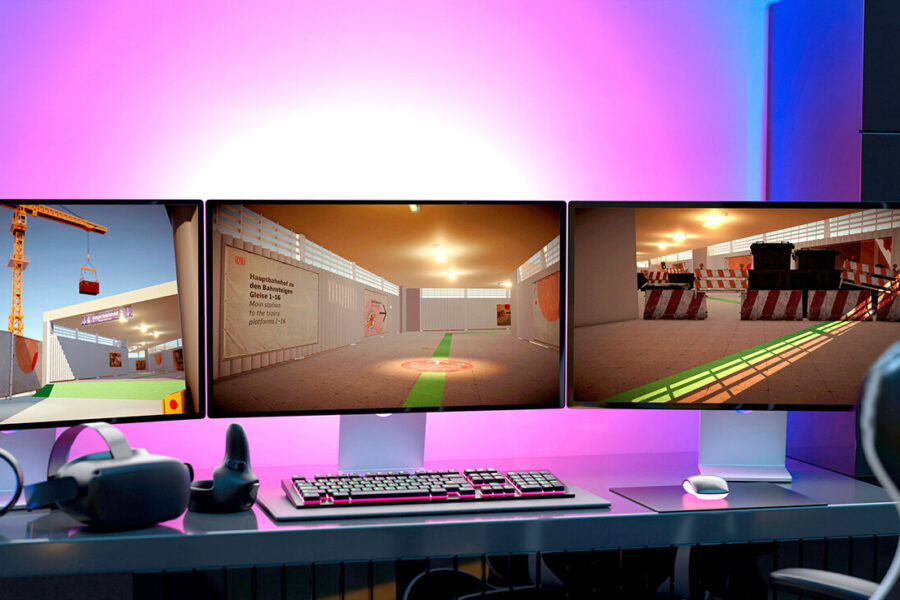 Drei Monitore mit virtueller Umgebung, VR-Headset auf Schreibtisch.