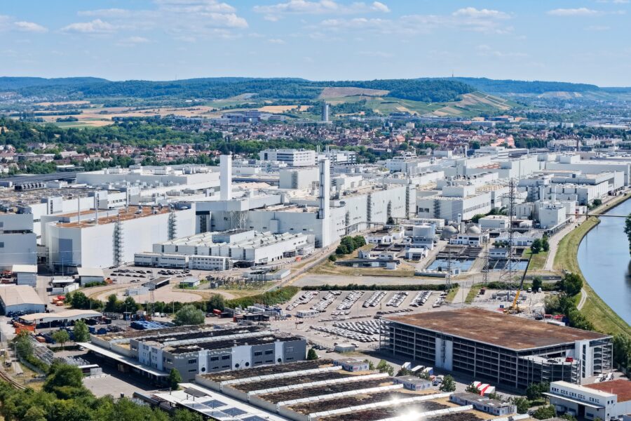 Großes Fabrikgelände mit mehreren weißen Gebäuden, umgeben von Landschaft.