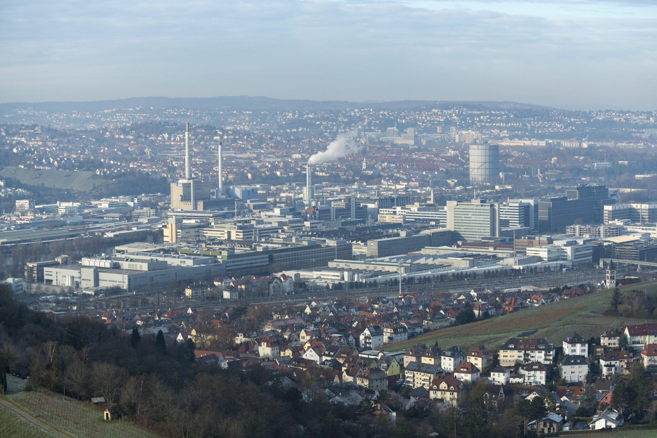 Industrieanlagen und Wohngebäude in einer weitläufigen Stadtlandschaft.