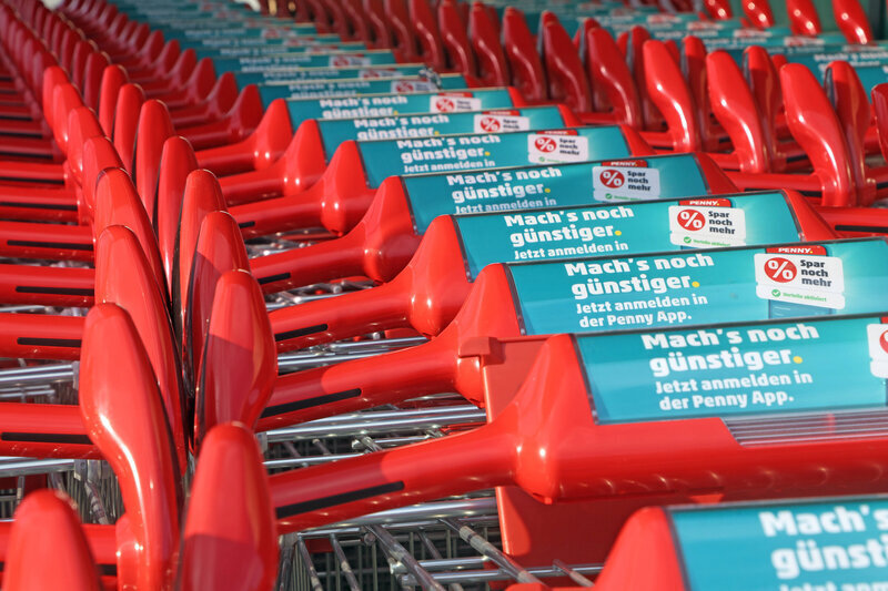 Rote Einkaufswagen in Reihe mit Aufschrift auf Griffen.