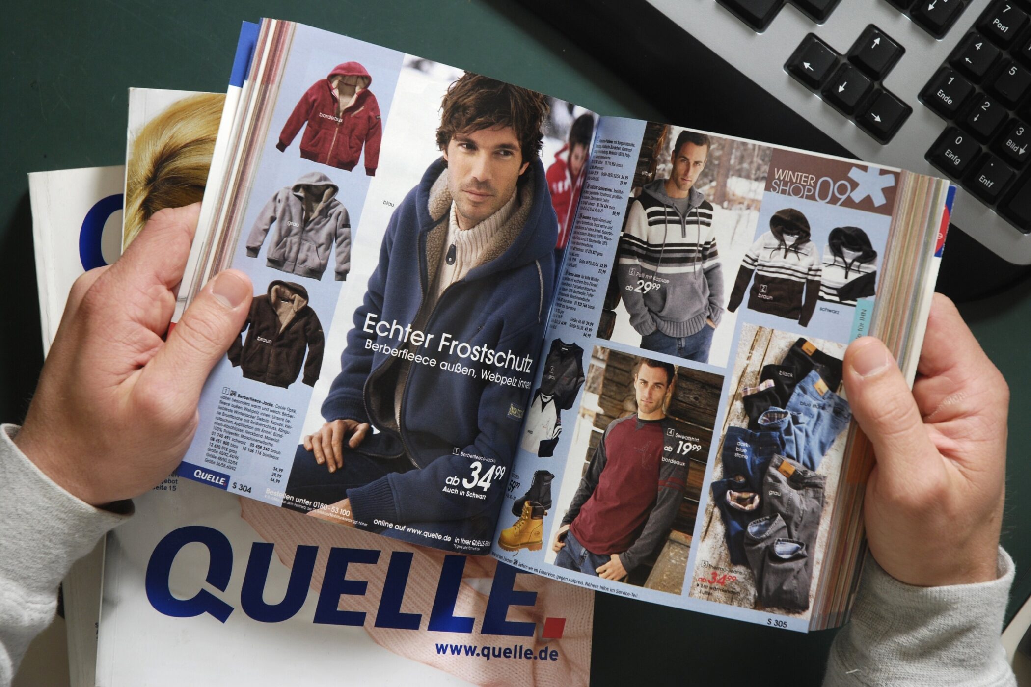 Person blättert in einem Kleidungskatalog, Titel "QUELLE". Verschiedene Jacken abgebildet.