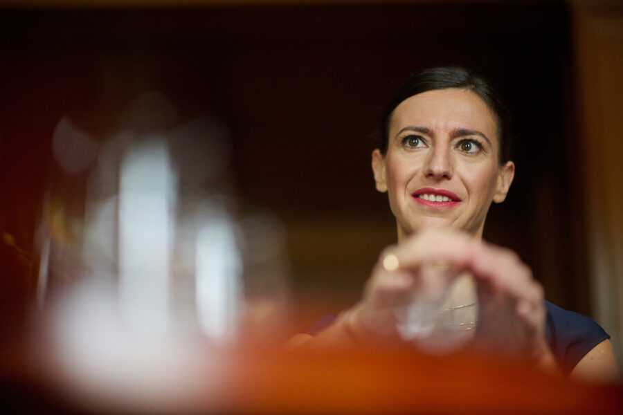 Frau berührt ein Glas vor unscharfem Hintergrund.