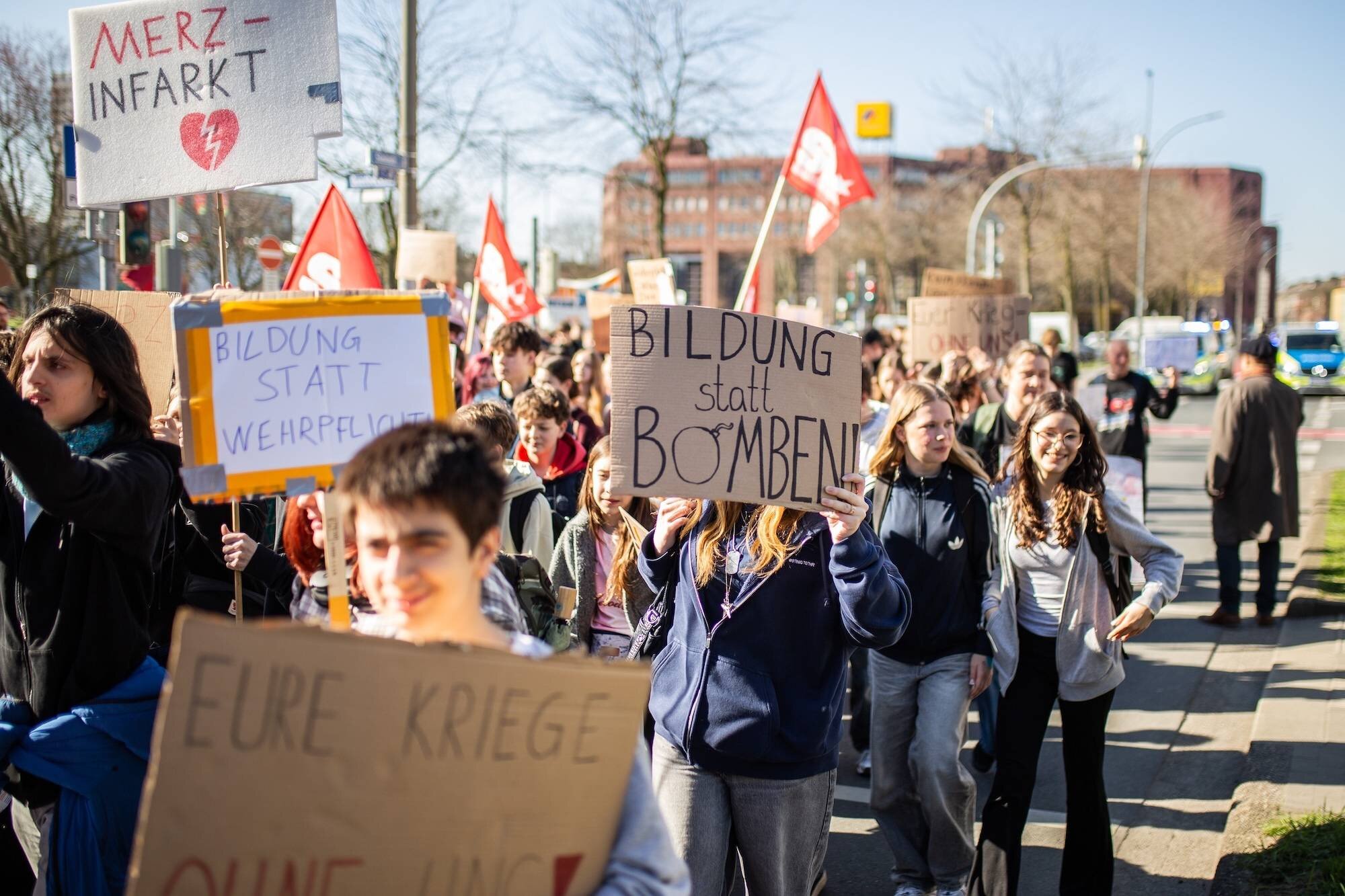Gruppe von Menschen hält Schilder mit politischen Botschaften bei einer Demonstration.