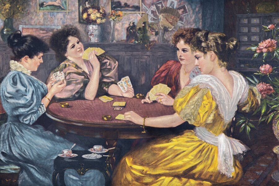 Vier Frauen sitzen an einem Tisch und spielen Karten.