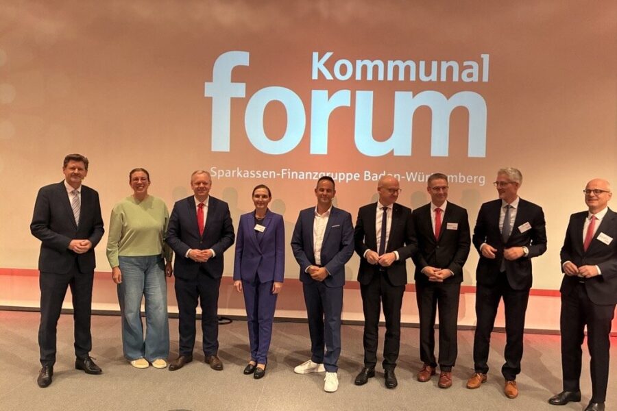 Neun Personen stehen auf einer Bühne vor der Schrift "Kommunal Forum".