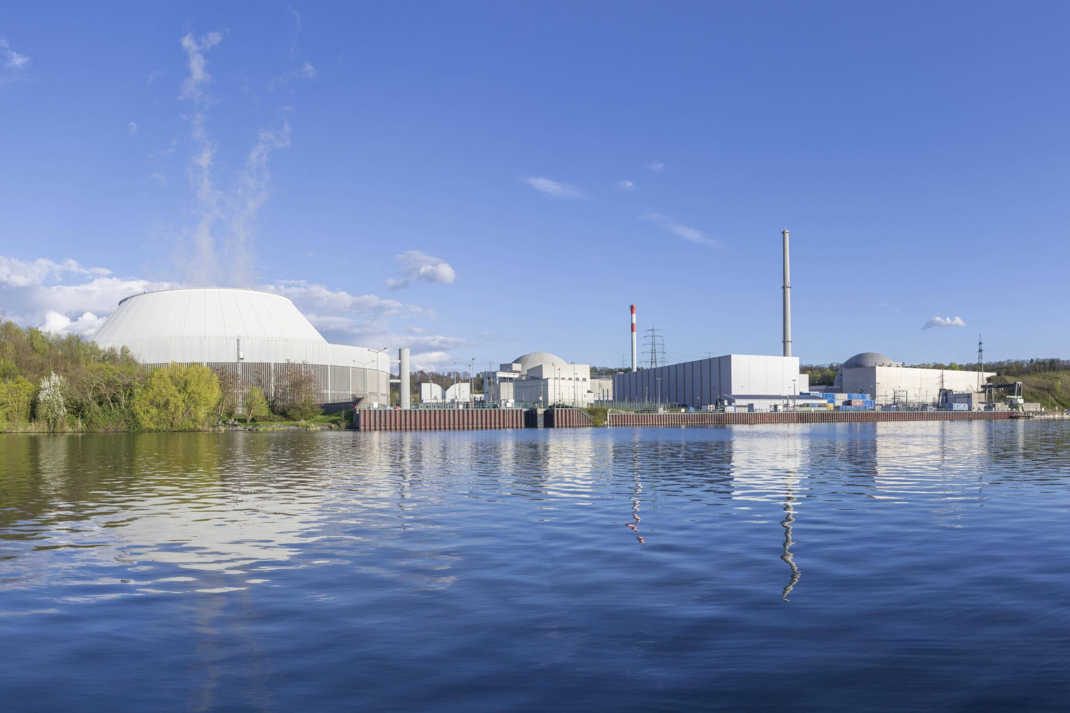 Industrieanlagen am Flussufer, blauer Himmel mit Wolken.