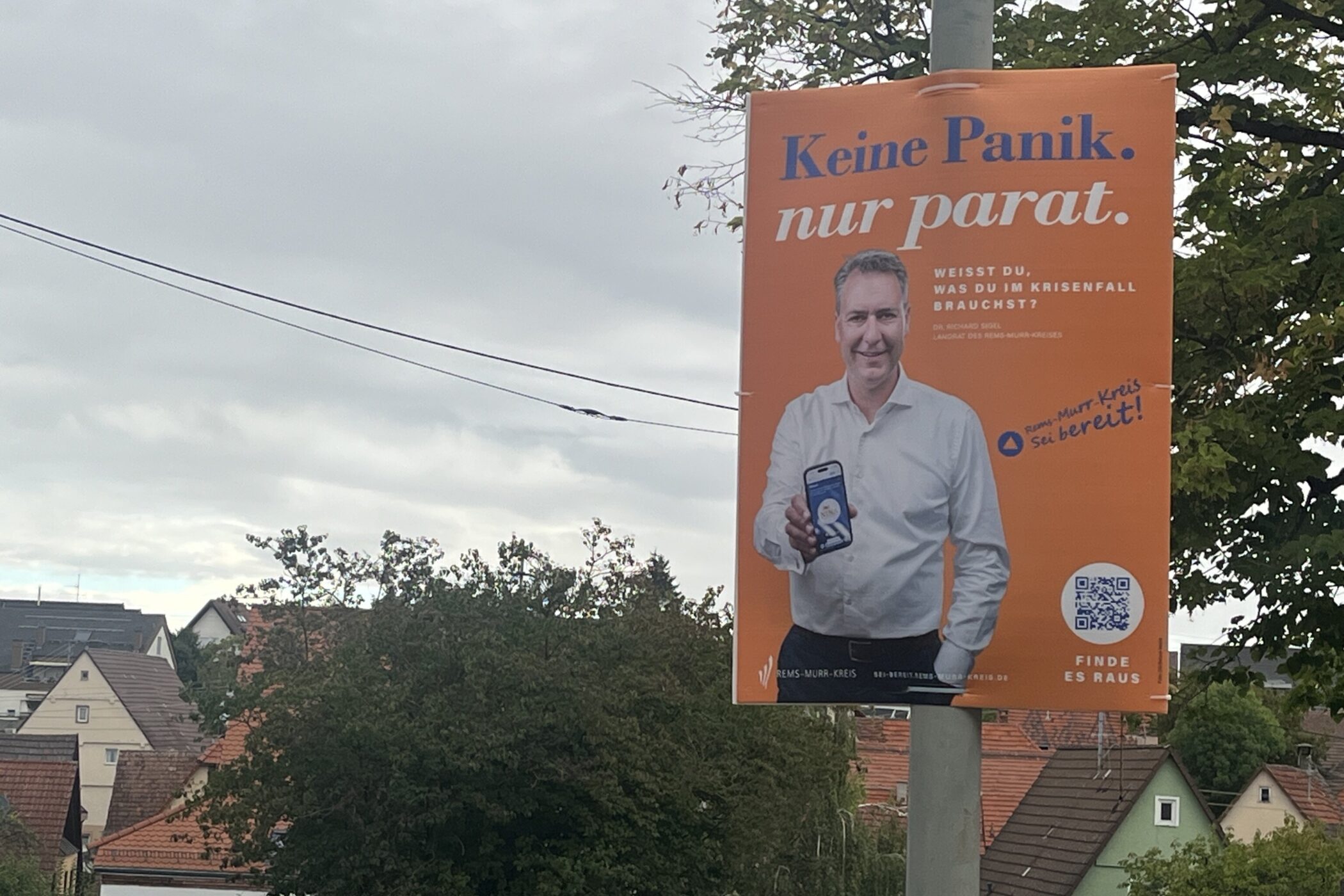 Orange Plakat an Laternenpfahl mit Text "Keine Panik. nur parat."