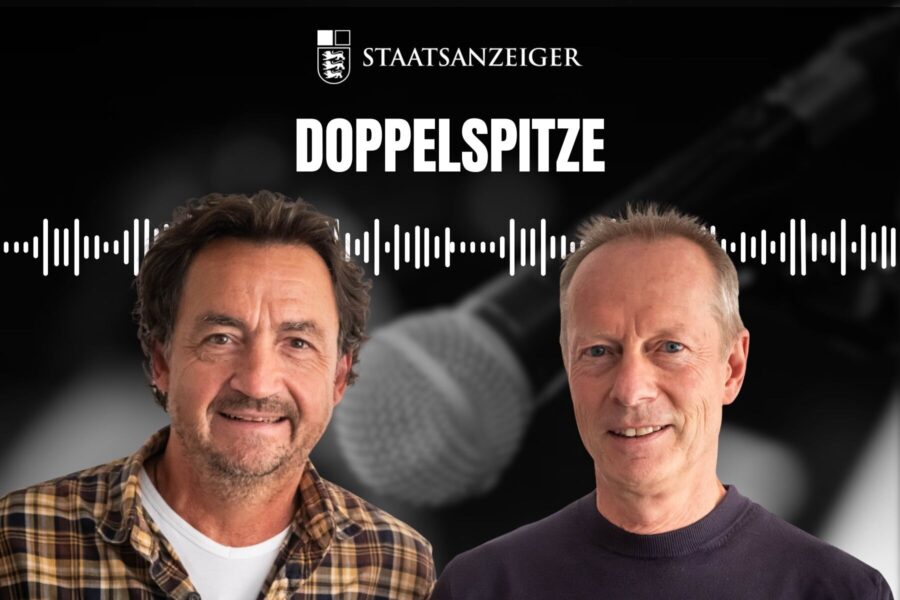 Zwei Männer vor einem Mikrofon, Schriftzug: „STAATSANZEIGER DOPPELSPITZE“.