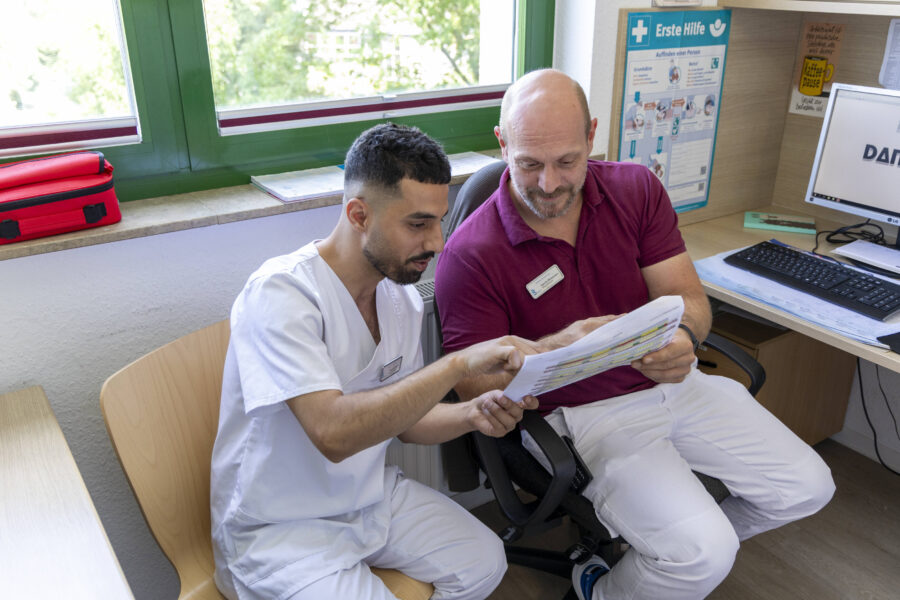 Zwei Männer in medizinischer Kleidung besprechen Dokumente in einem Büro.