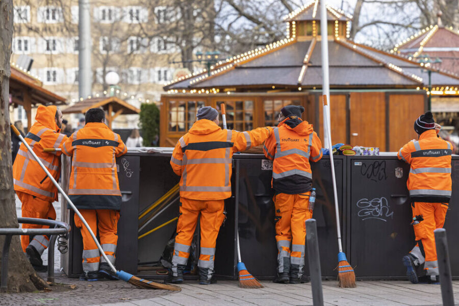 Fünf Personen in orangefarbener Arbeitskleidung bei Reinigungsarbeiten.