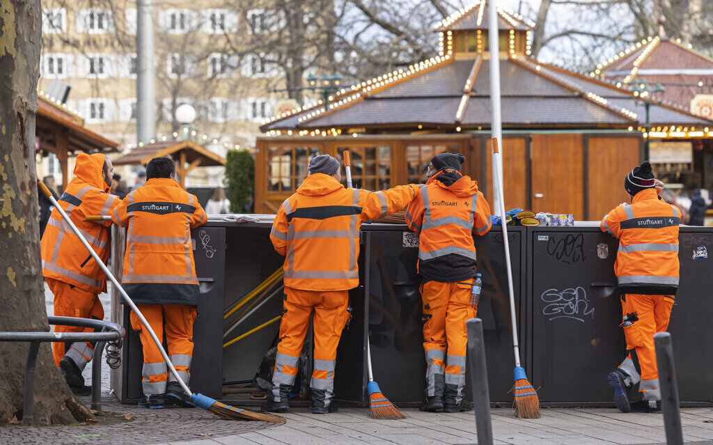 Fünf Personen in orangefarbener Arbeitskleidung bei Reinigungsarbeiten.
