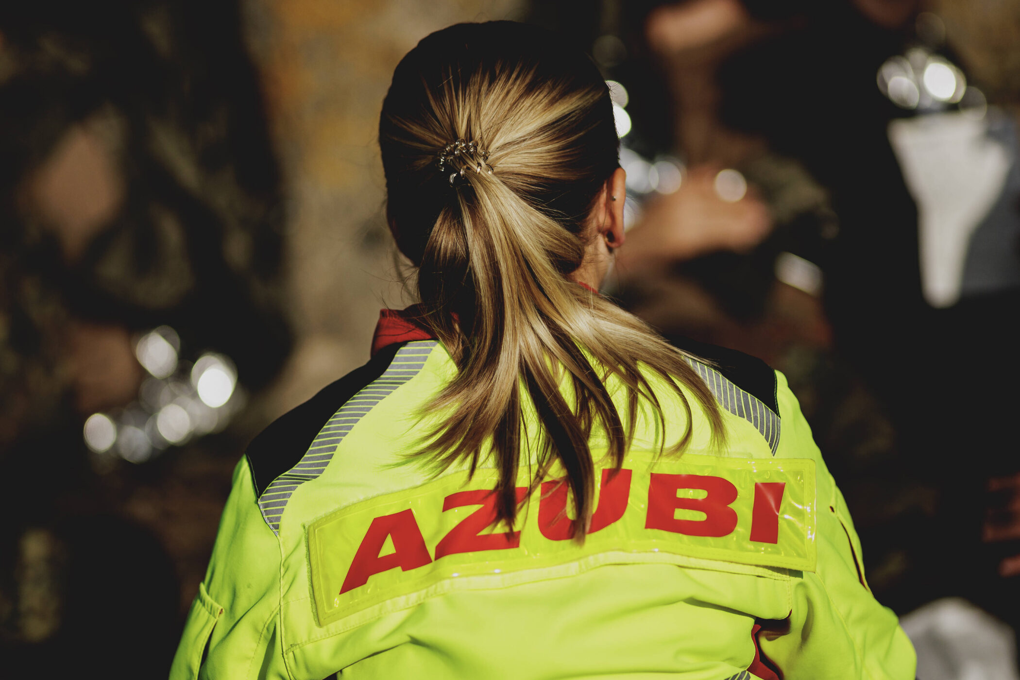 Person in gelber Jacke mit der Aufschrift "AZUBI".