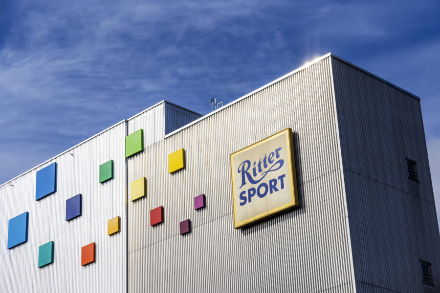 Industrielles Gebäude mit bunten Quadraten und "Ritter Sport"-Schild.
