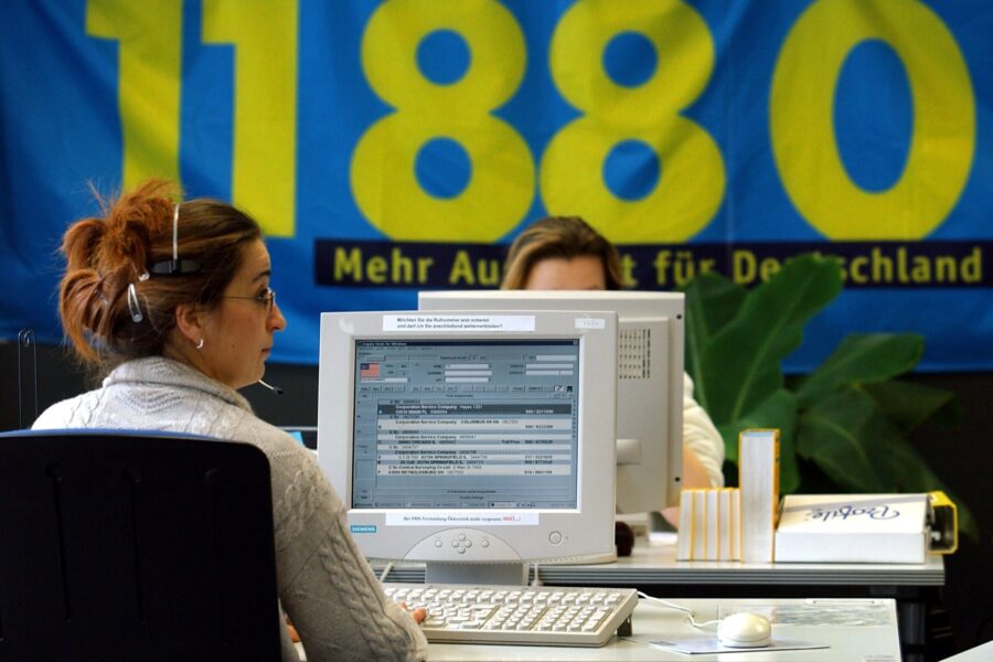 Zwei Personen an Computern, im Hintergrund großes Banner "11880".