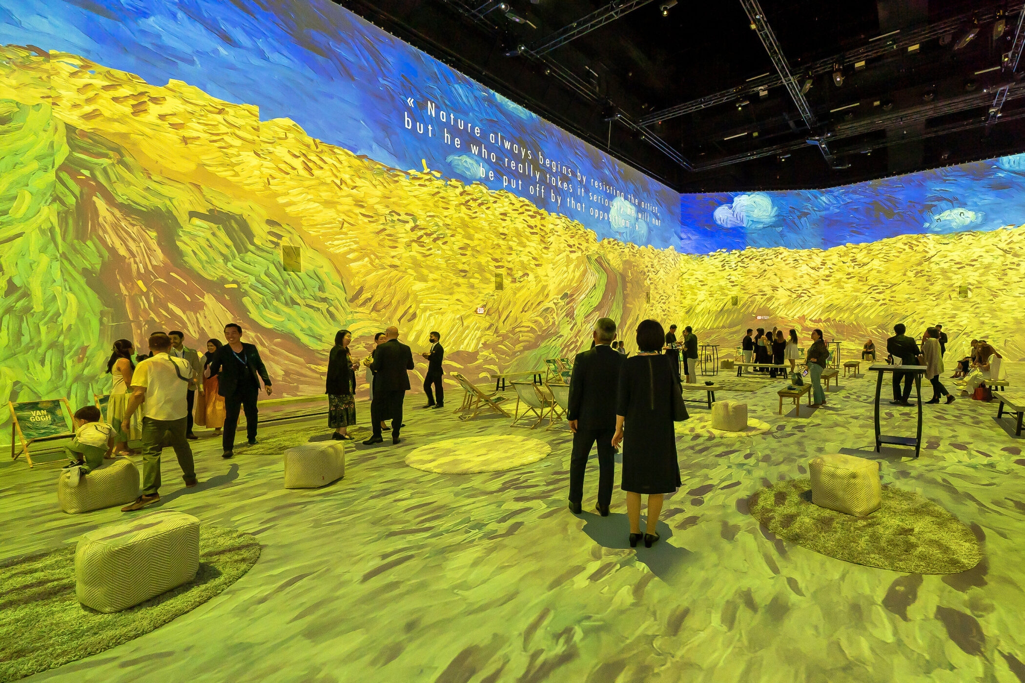 Mehrere Personen in einem Raum mit Projektionen von Van-Gogh-Werken.